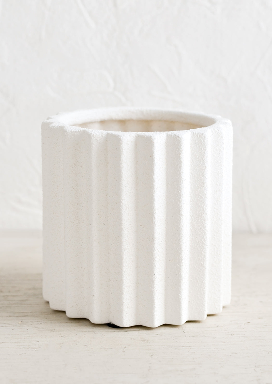 A matte white ceramic planter in grooved, geometric shape.