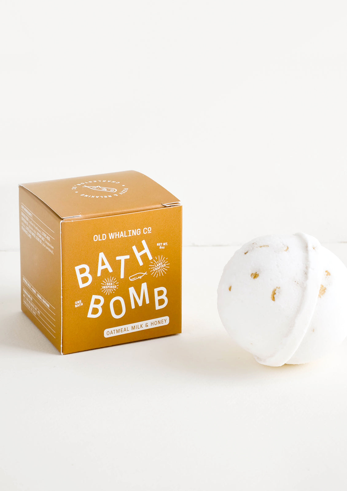 White colored, round bath bomb with brown box packaging