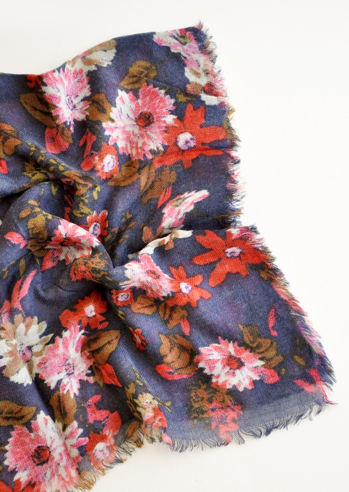 Close up shot of scarf with dark blue background and multi-colored pink and red floral pattern 