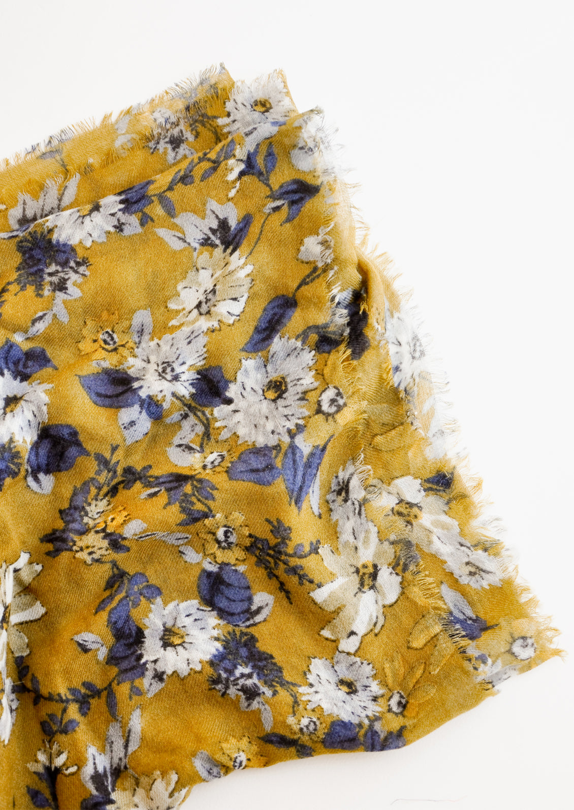 Close up shot of scarf with dark yellow background and multi-colored blue and white floral pattern 