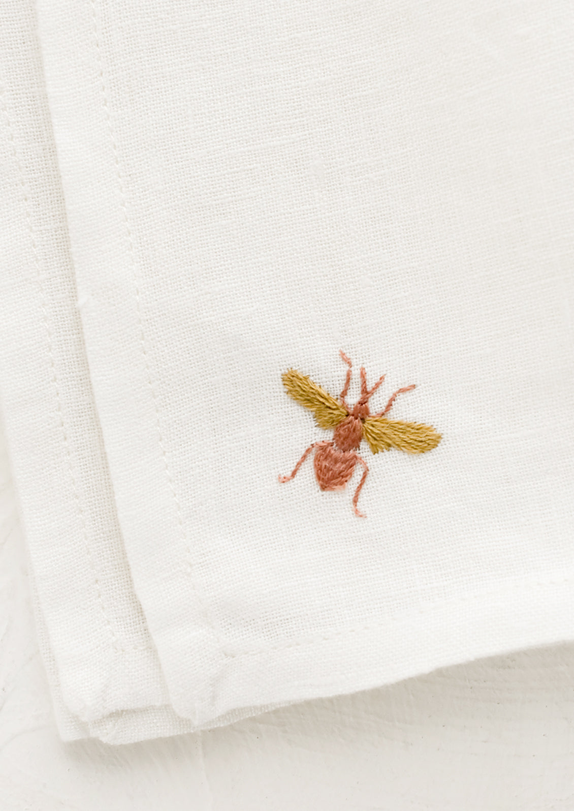 Embroidered bee on white linen.