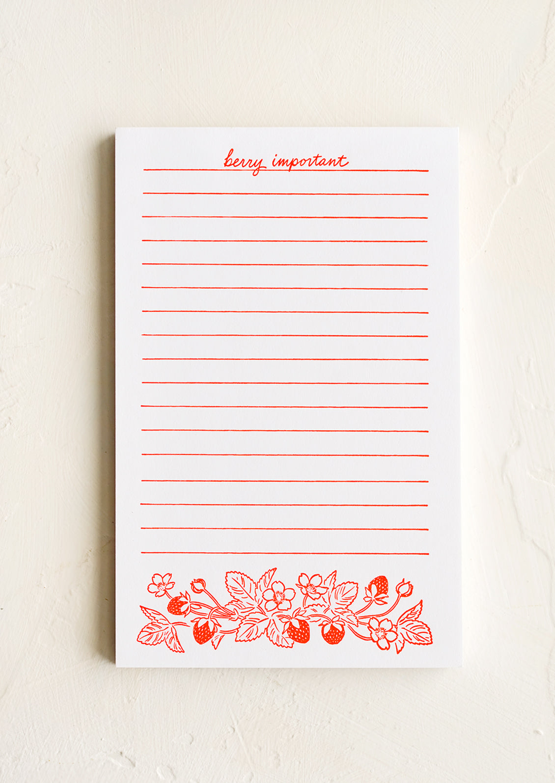 A white letterpress printed notepad with red lines and berry print.