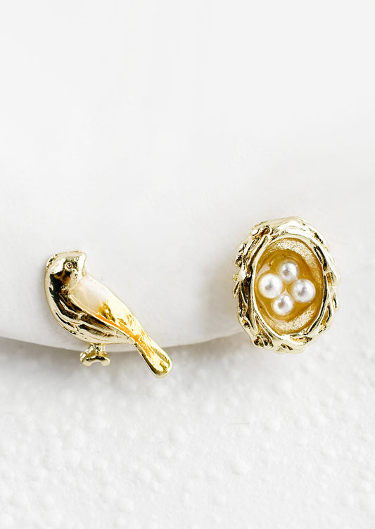 A pair of stud earrings, one bird and one nest with pearl eggs.