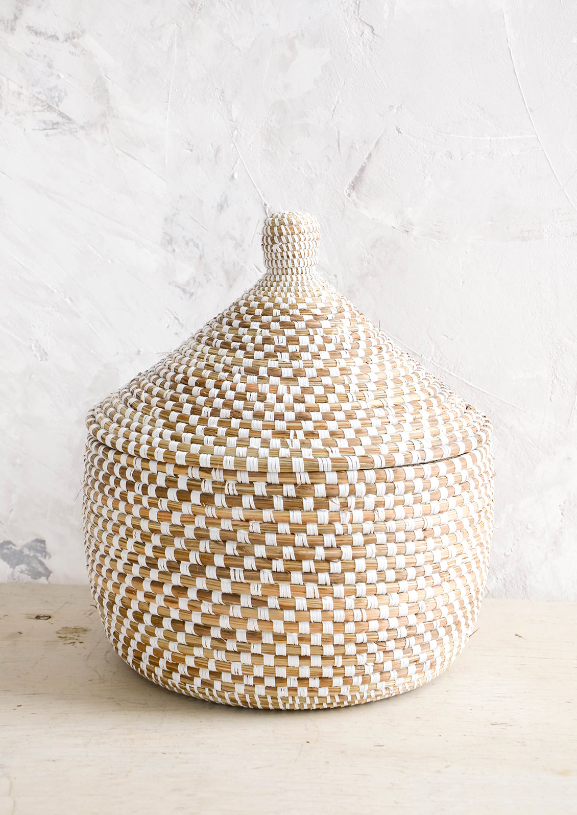 Lidded storage basket made from natural grass with white checkered pattern