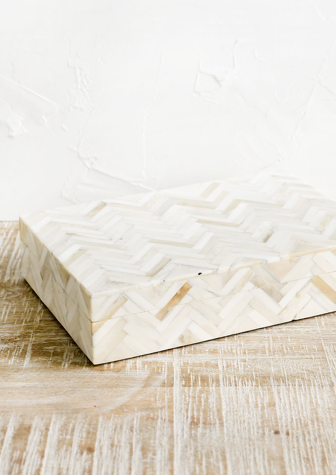 A rectangular storage box in cream colored herringbone pattern.