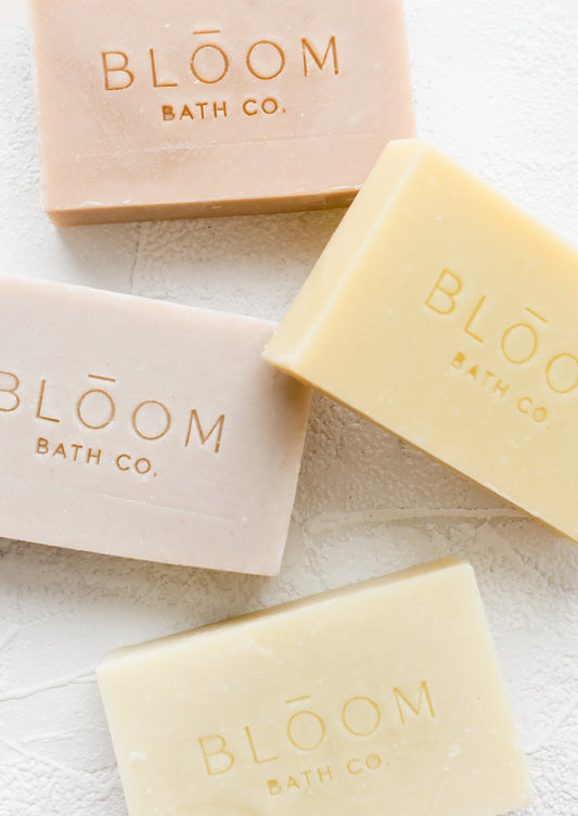 Four rectangular bars of soap in pastel colors with logo imprint.