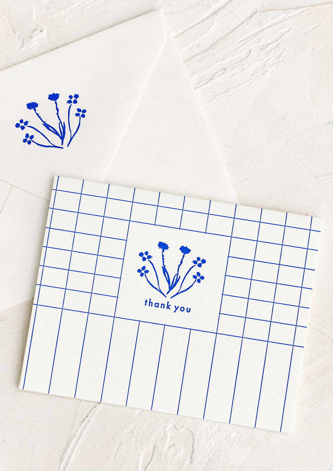 A blue and white grid patterned thank you card with drawn floral imagery.