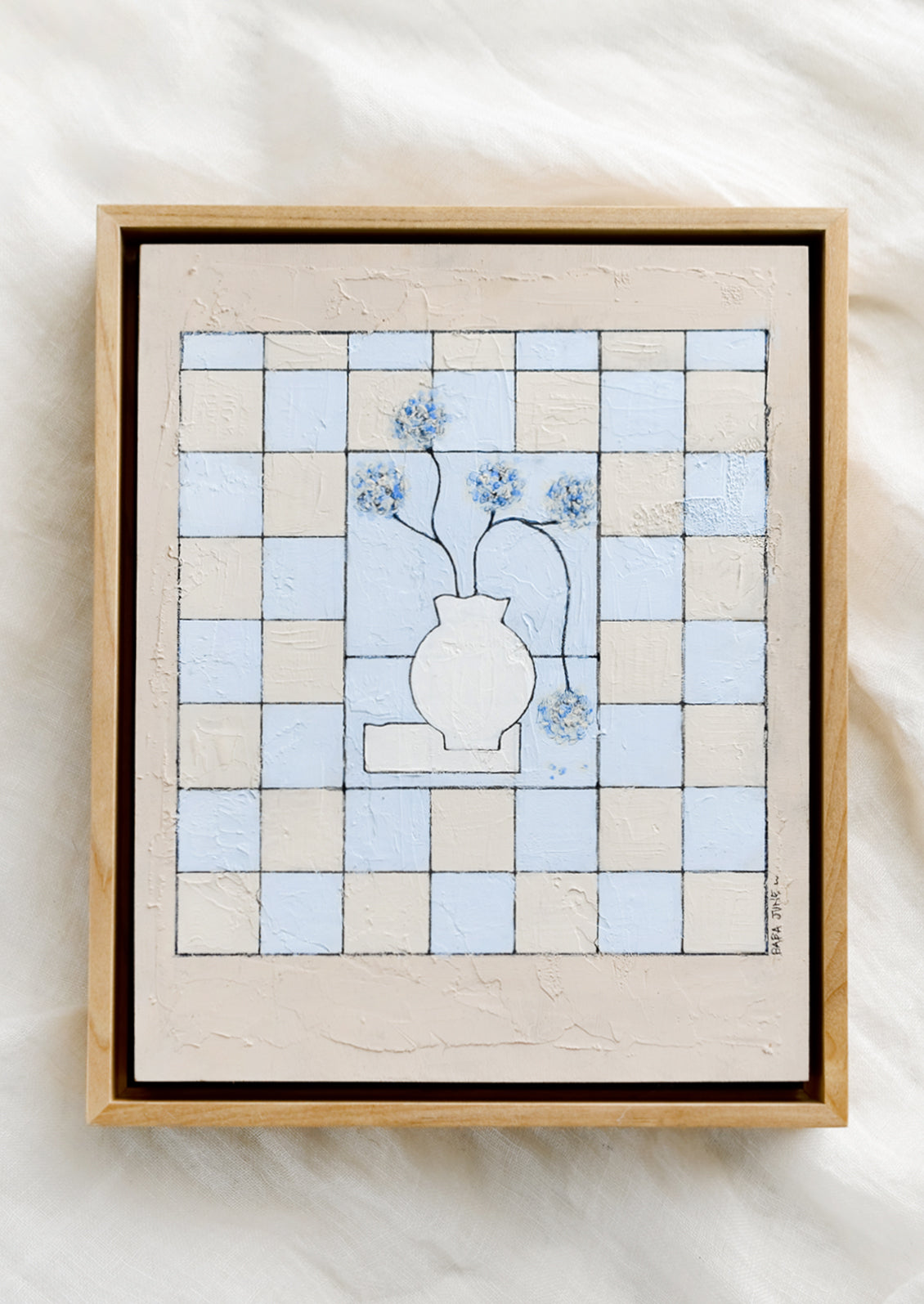 A framed original painting of still life vase with flowers on a checkered beige and periwinkle background.
