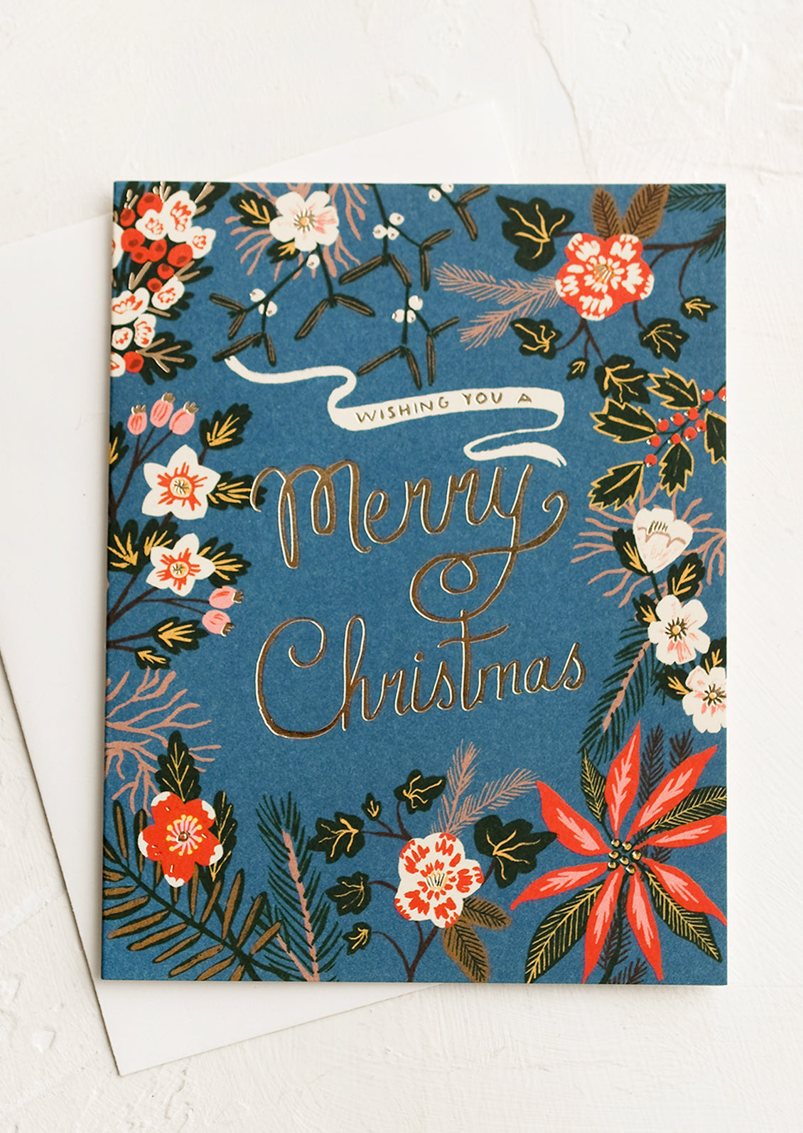 A greeting card with poinsettia floral print, gold text reads "Wishing you a merry christmas".