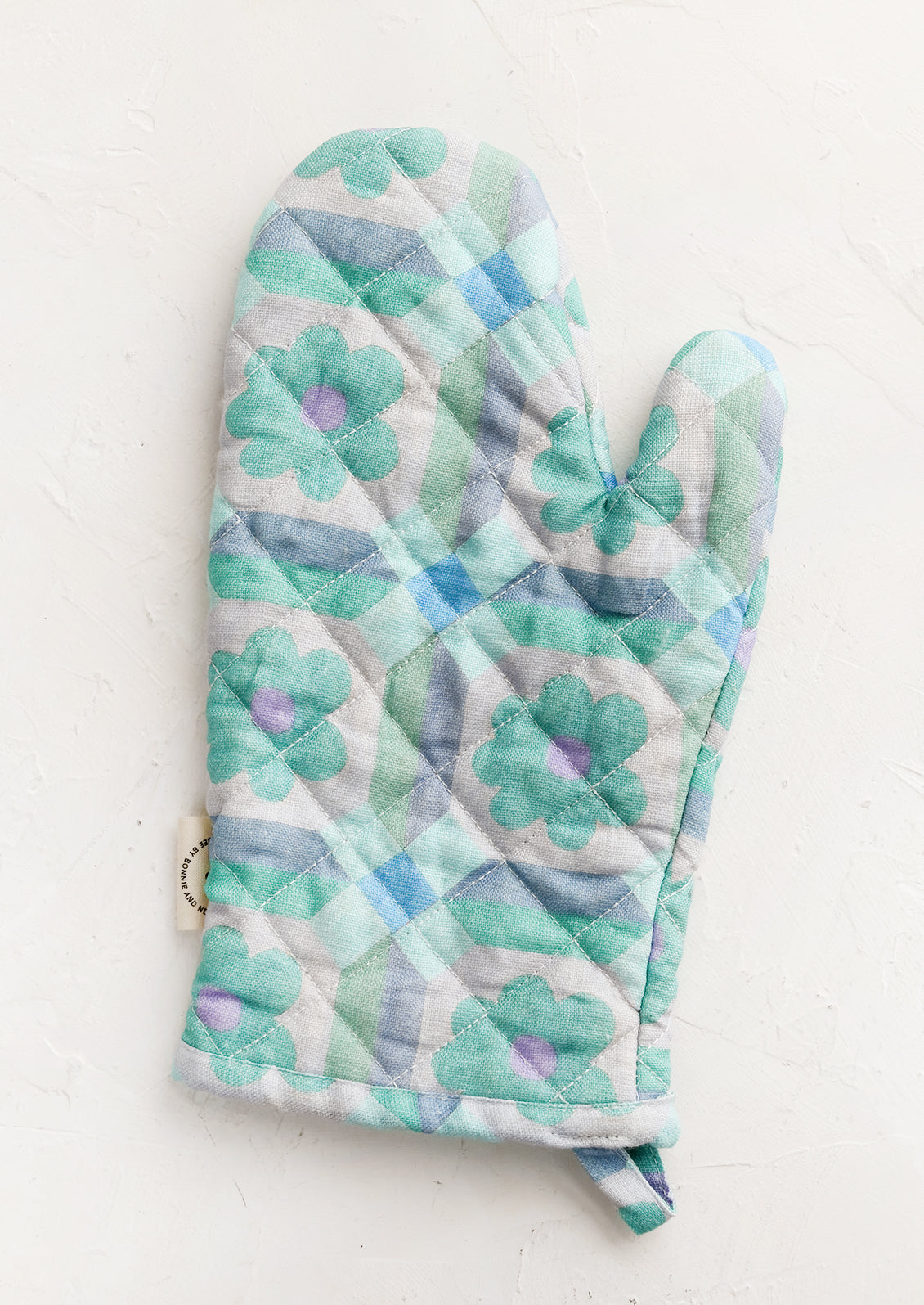 An oven mitt with retro floral pattern in aqua and lavender.