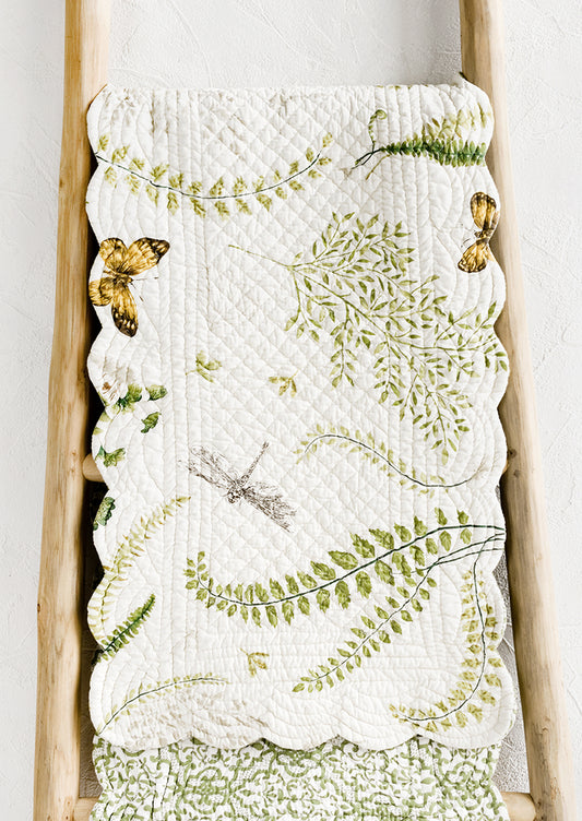A quilted table runner with fern print.