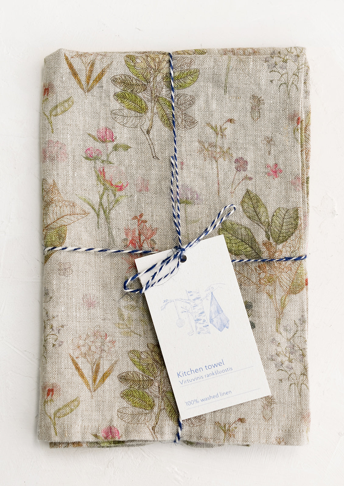 A botanically printed natural linen tea towel, folded and tagged.