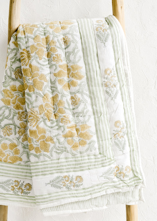 A padded quilt with block printed botanical print in green and yellow.