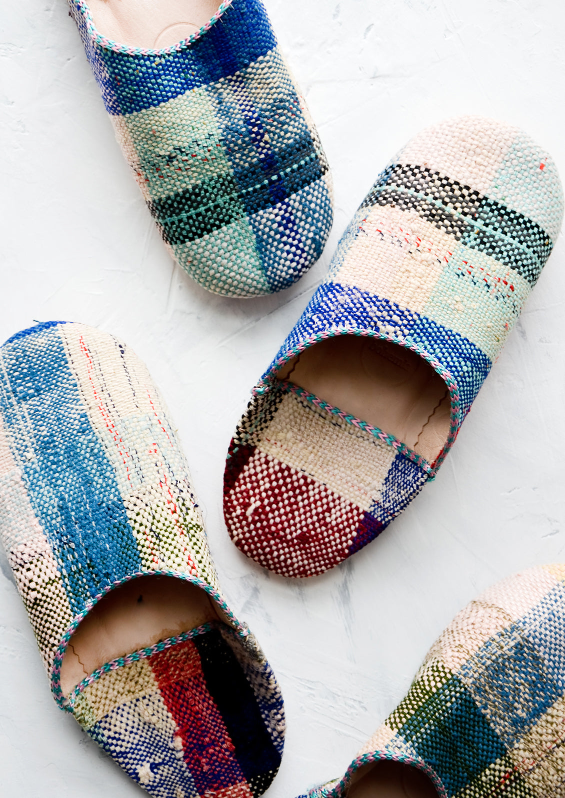 An assortment of house slippers made from colorful plaid fabric.