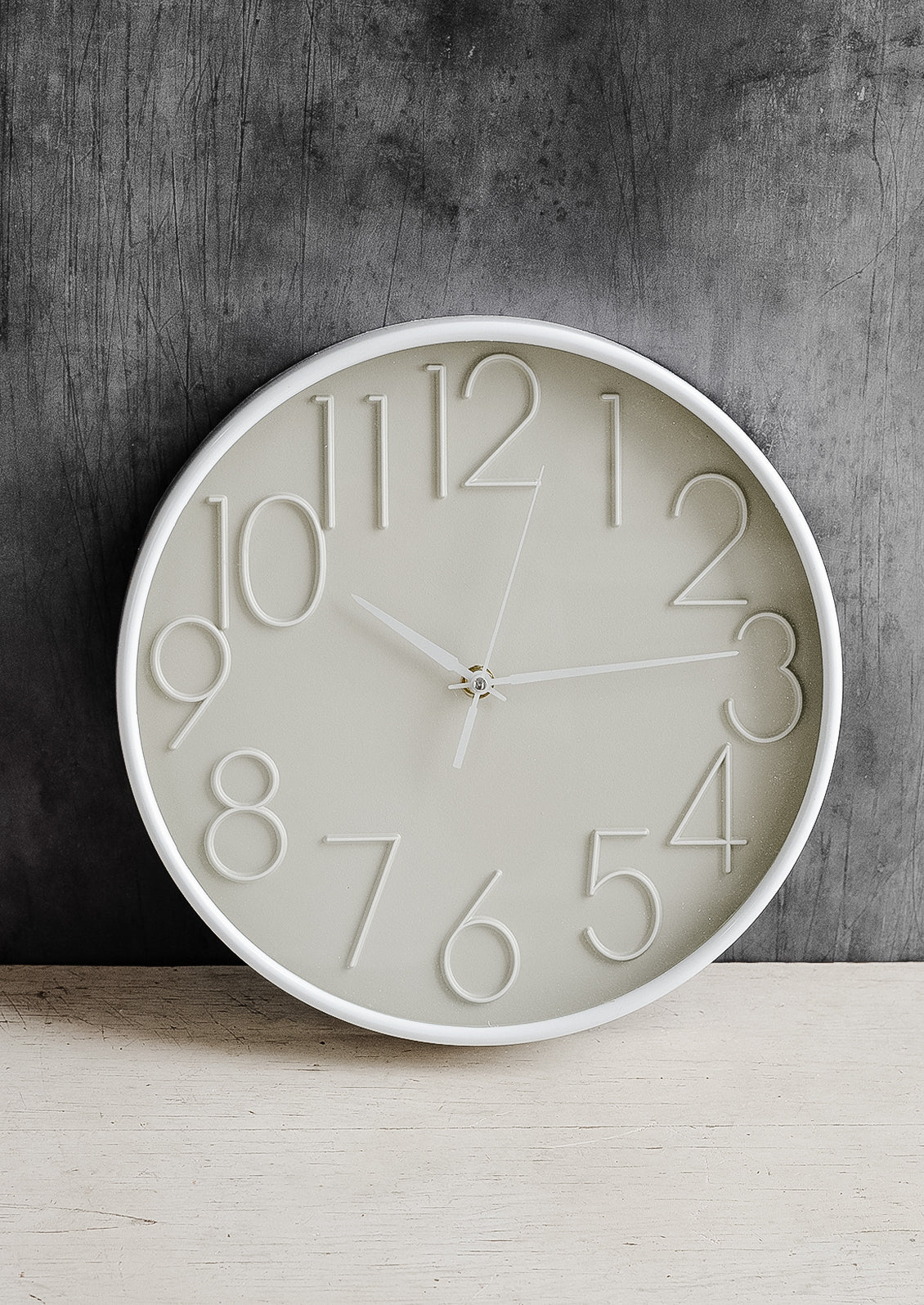 A circular wall clock with tan face and white border.