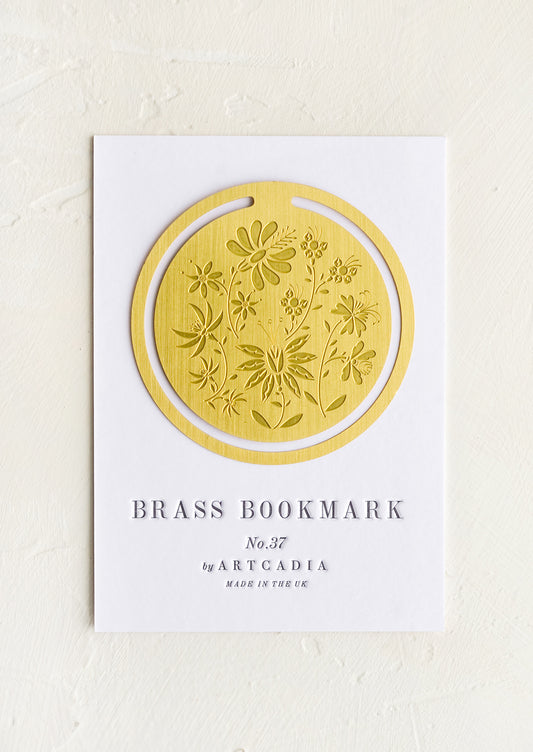 A circular brass bookmark with etched botanical pattern.