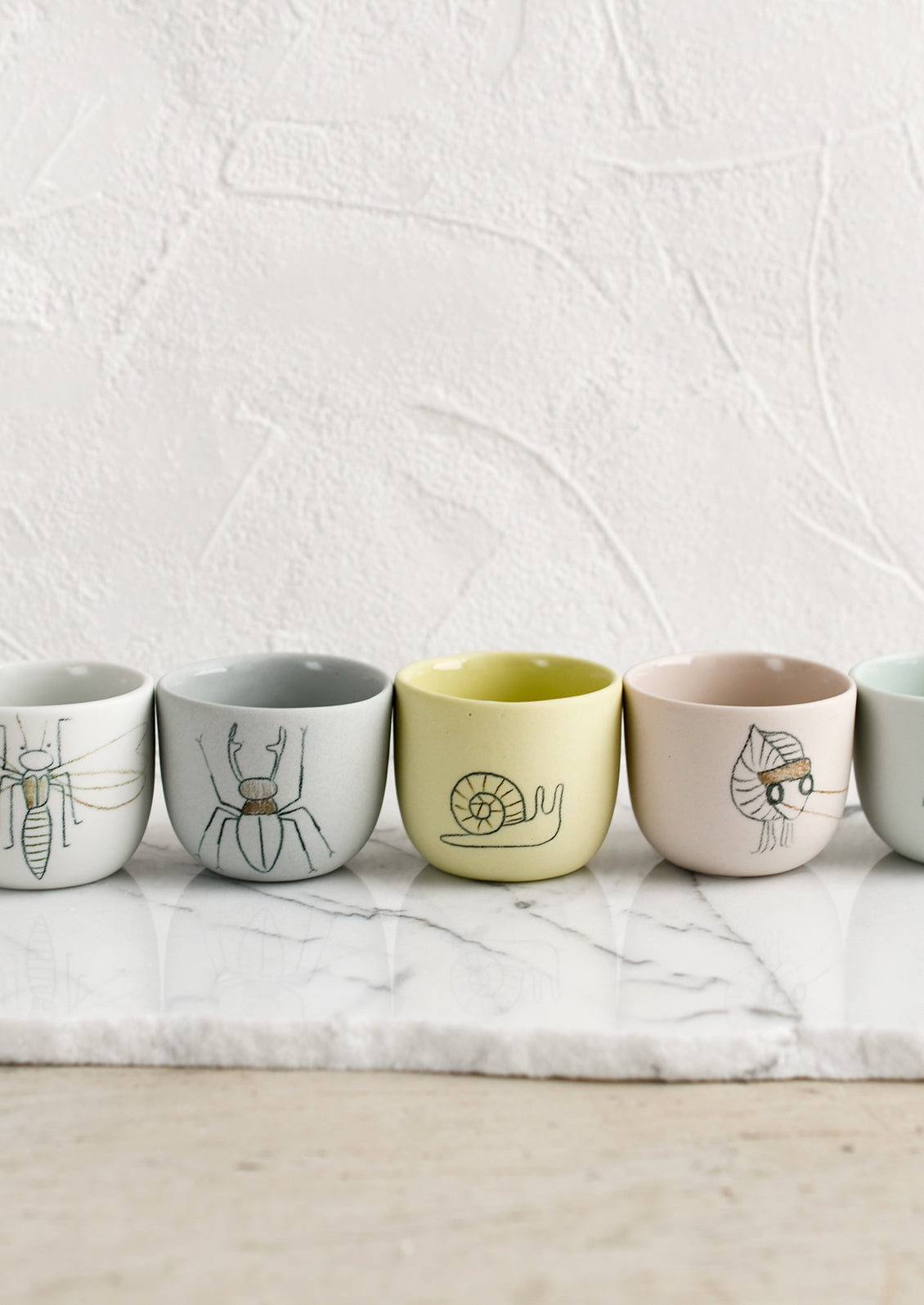Extra small cups in assorted colors with bug sketches.