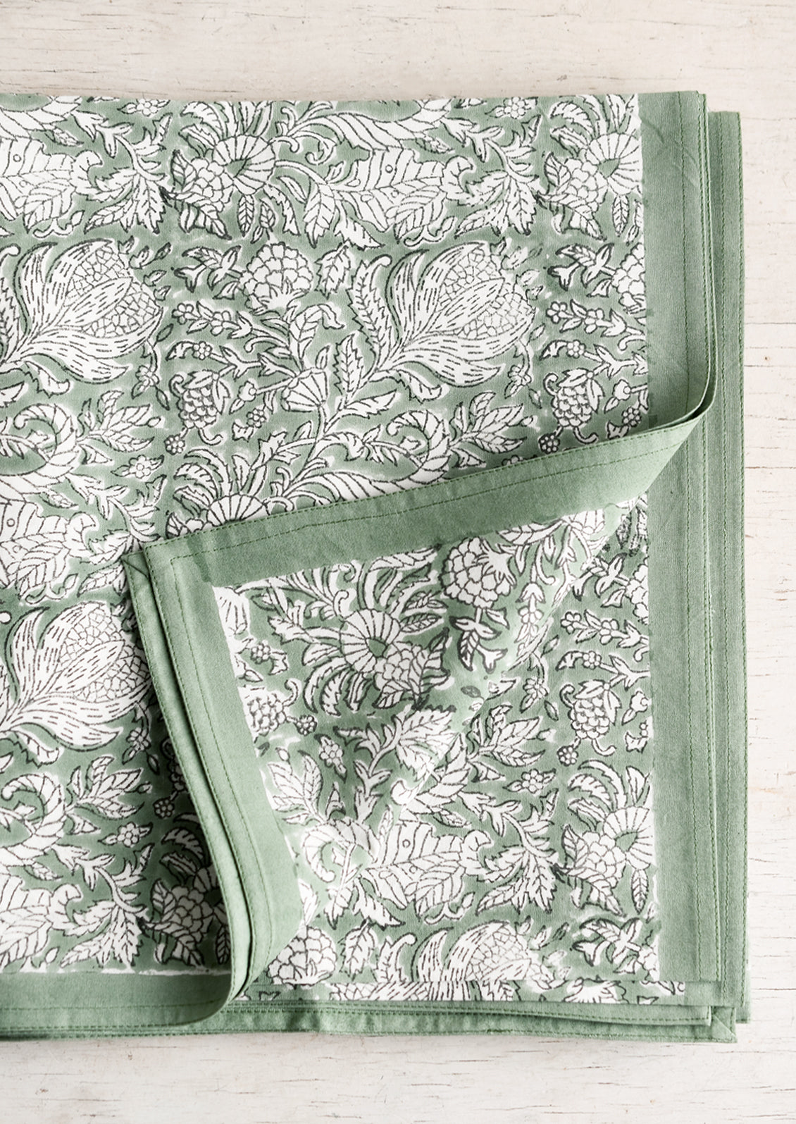 A block print tablecloth in ivy green with white and black floral print.