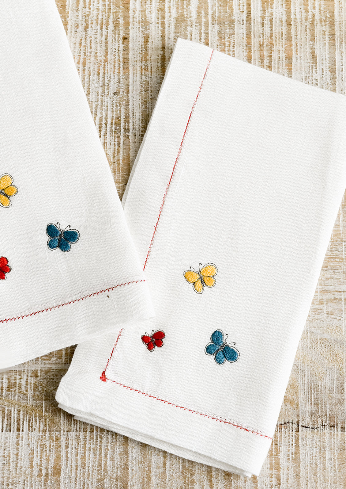 White linen napkins with primary colored butterfly embroidery.