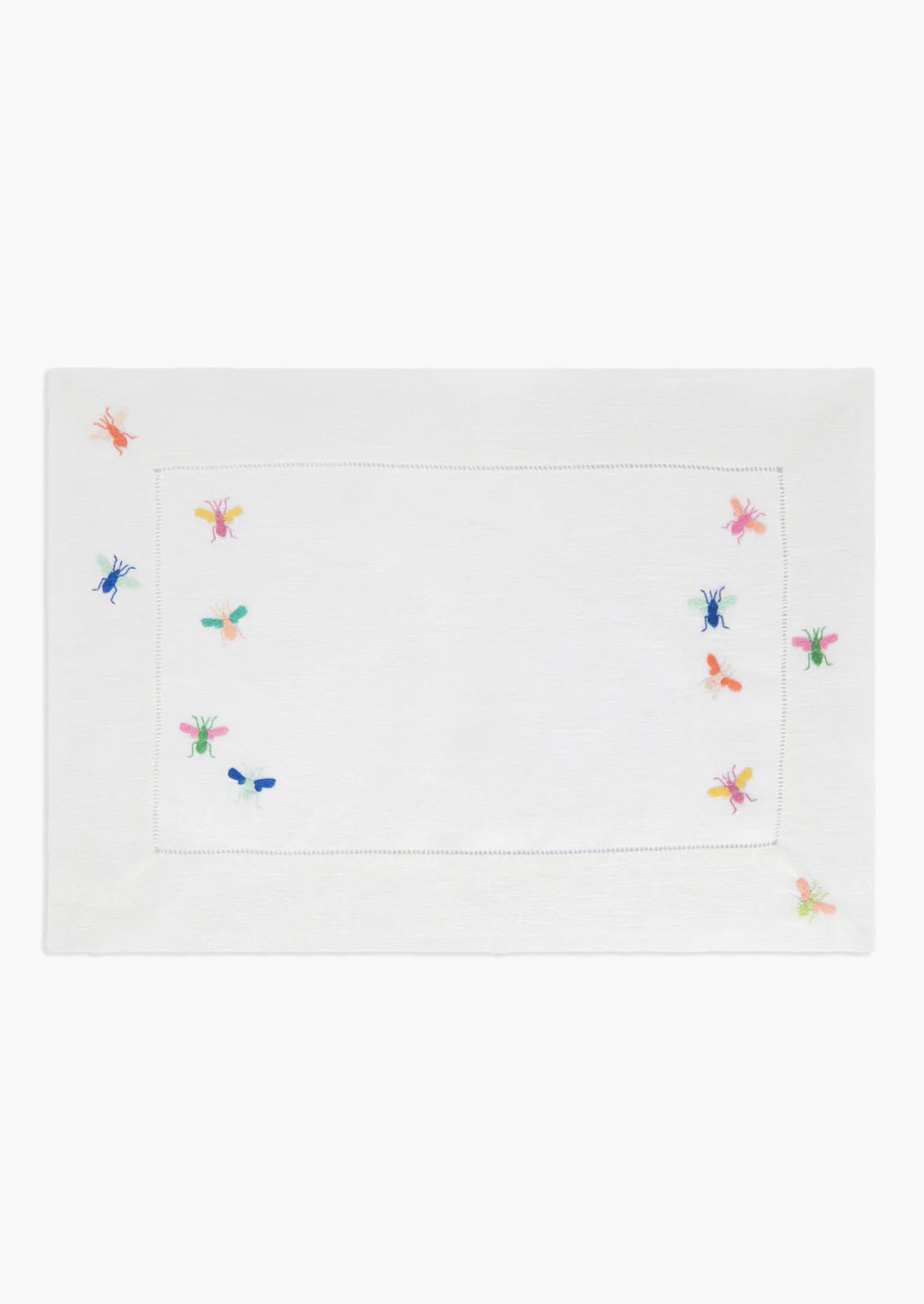 A white linen placemat with multicolor bee embroidery.