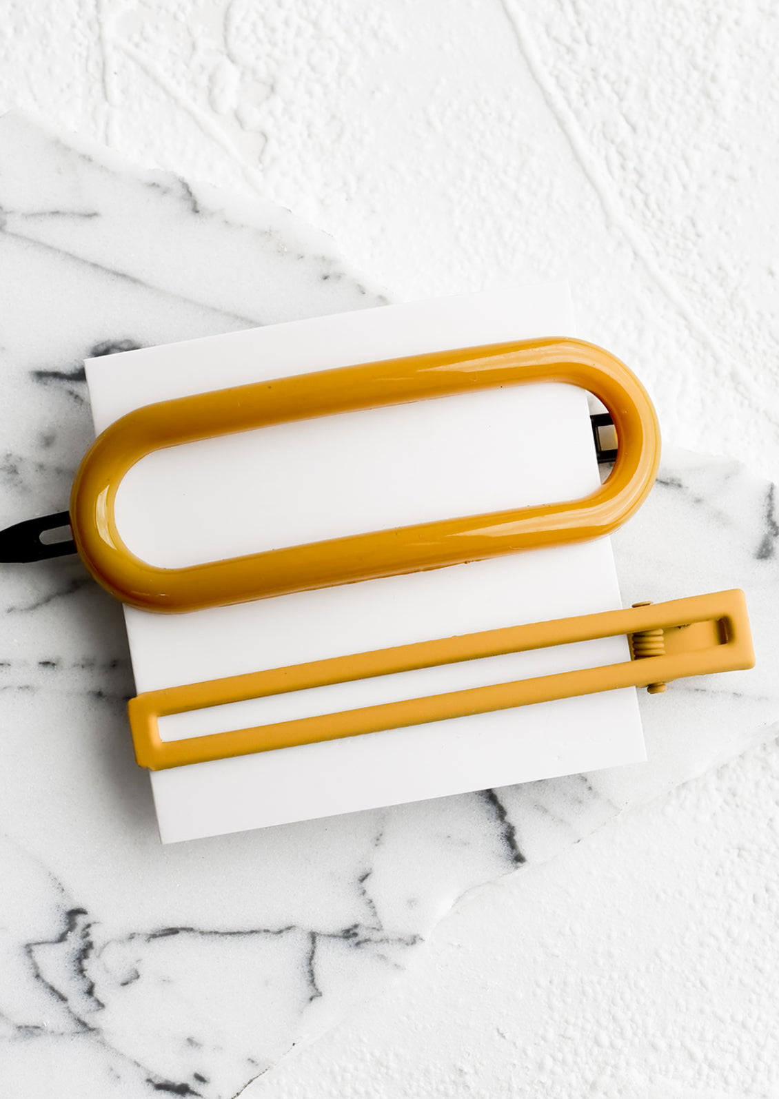 A pair of hair clips in oval and rectangular shapes in mustard.