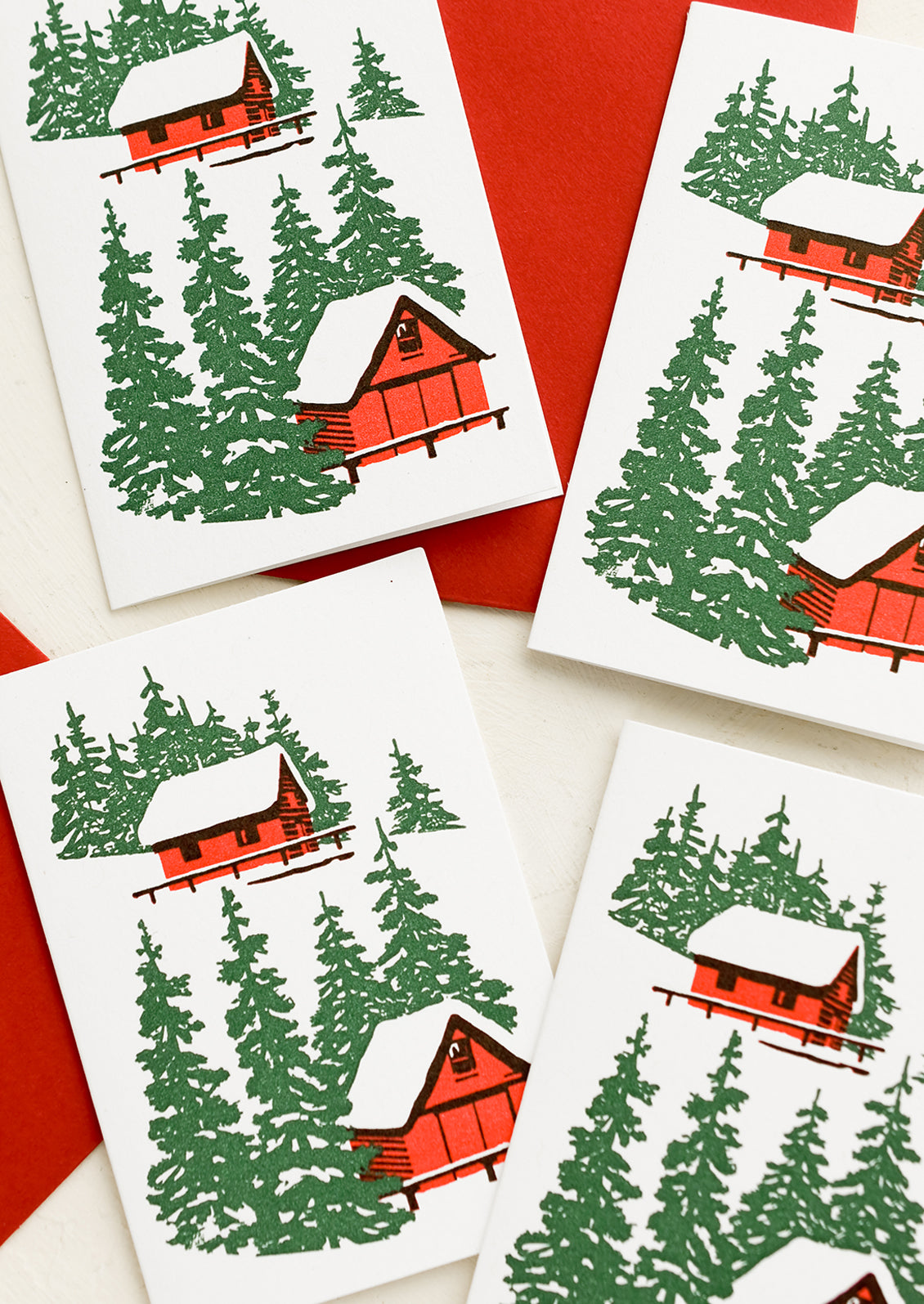 A set of letterpress mini enclosure cards with cabin in the woods print and red envelopes.