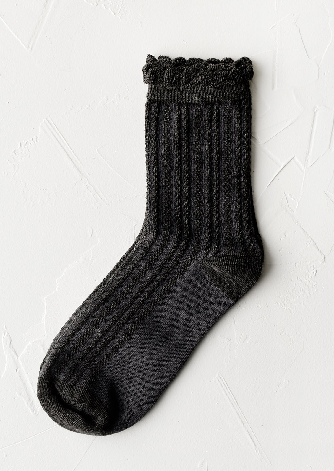 A pair of cable knit socks with ruffled ankle in charcoal.