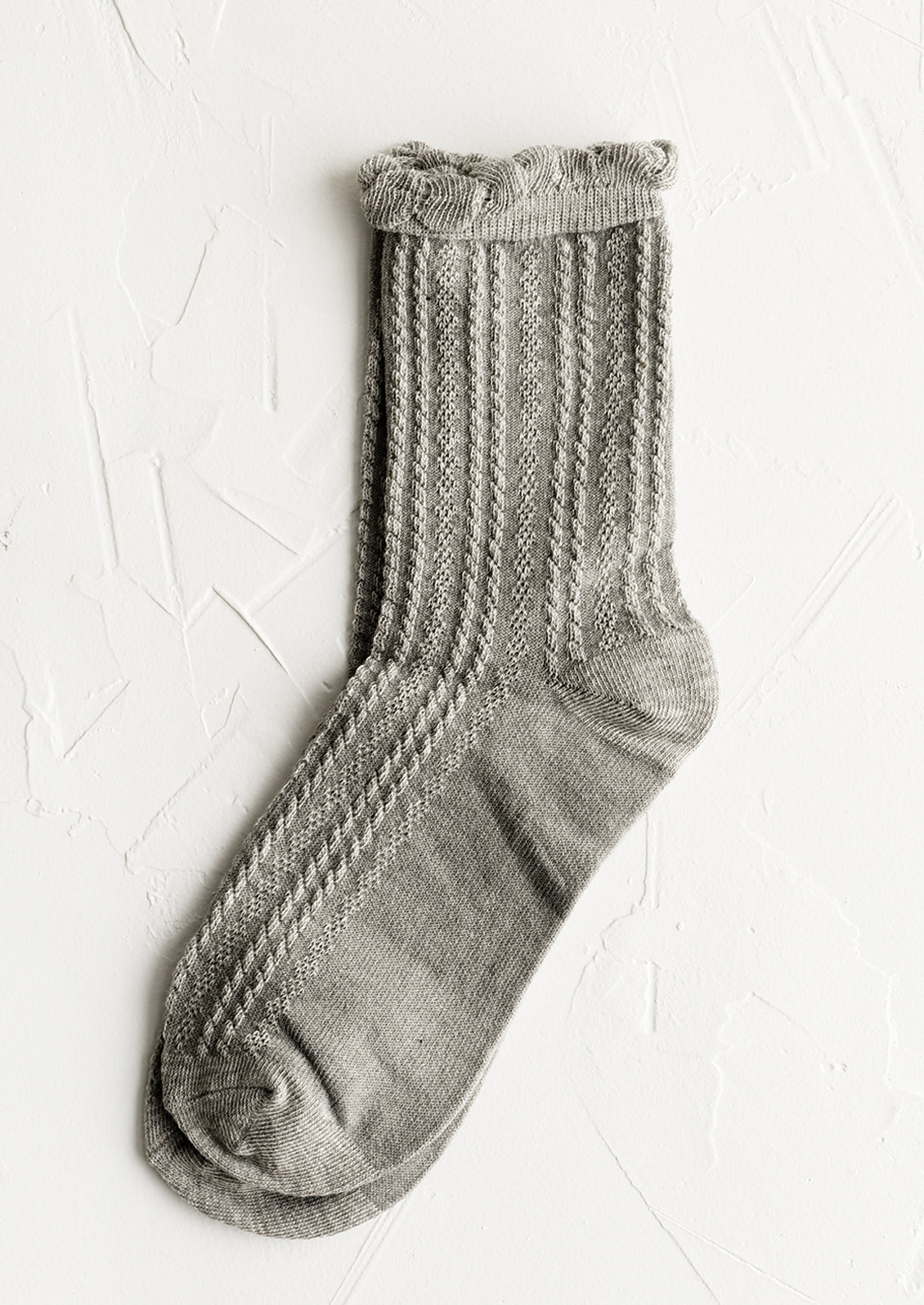 A pair of cable knit socks with ruffled ankle in heather grey.