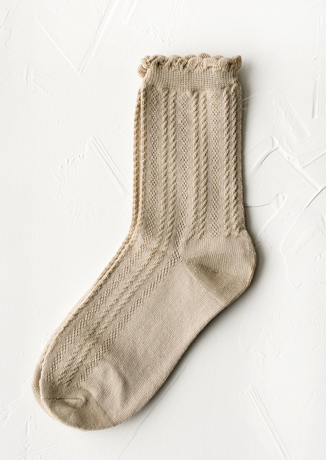 A pair of cable knit socks with ruffled ankle in tan.