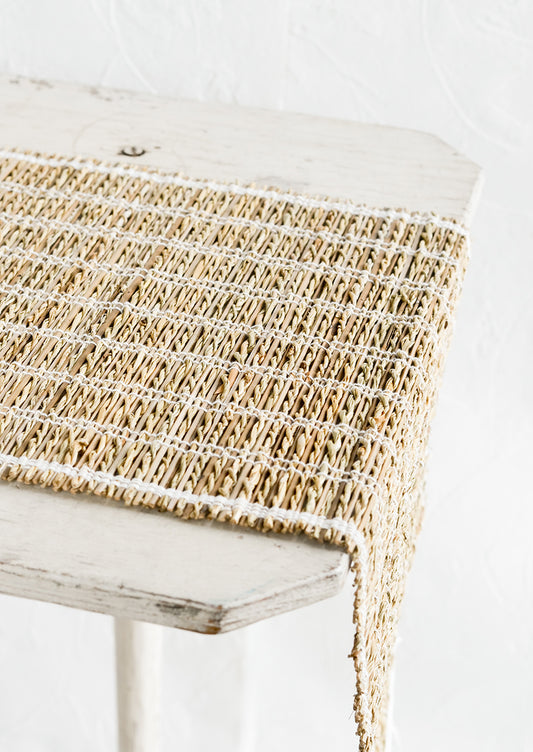 A table runner made of natural banana fiber with white stitching.