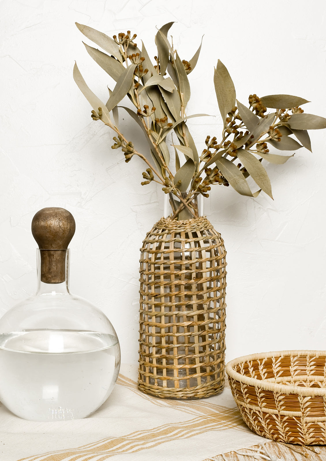  A glass carafe with seagrass wrapped vase.