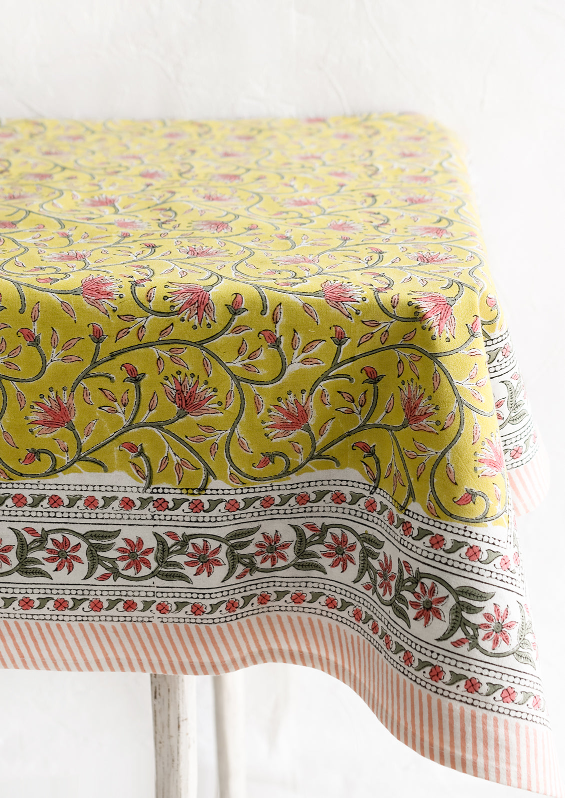 A block printed tablecloth in yellow, pink and green floral.
