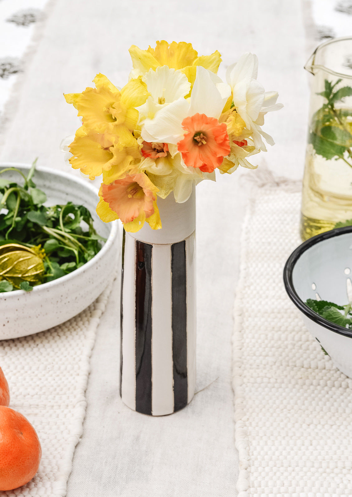 A black and white vase on a table with daffodils.