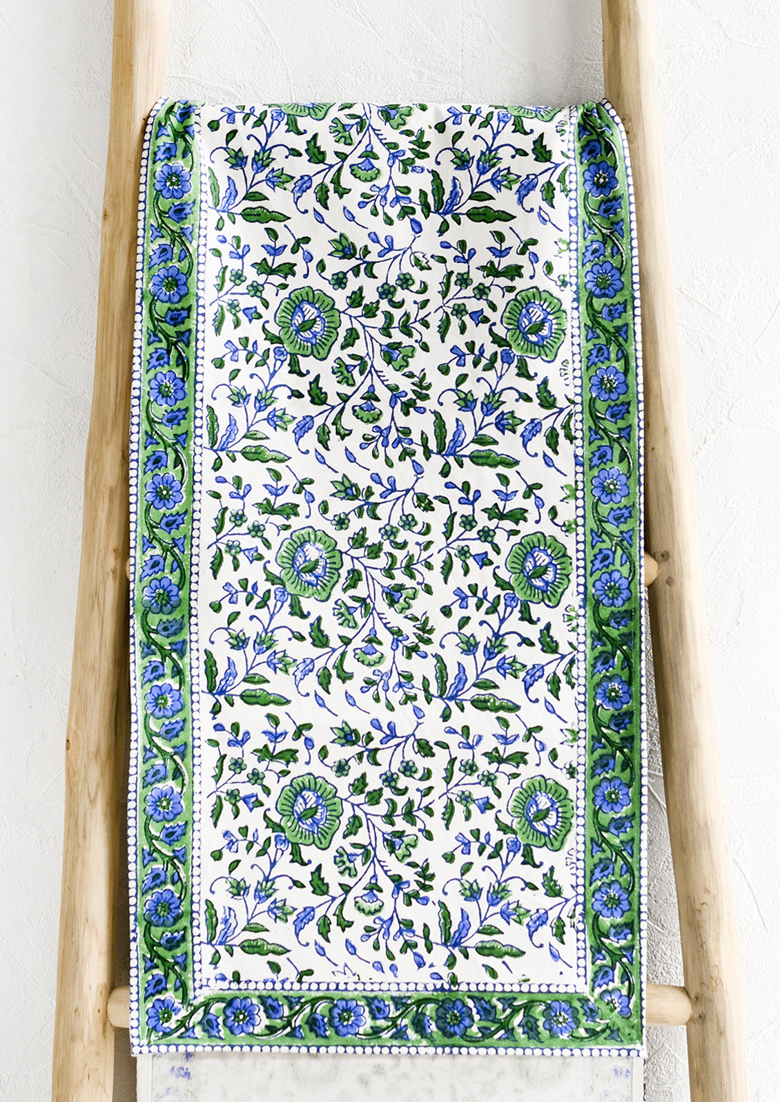 A table runner in blue and green floral block print.