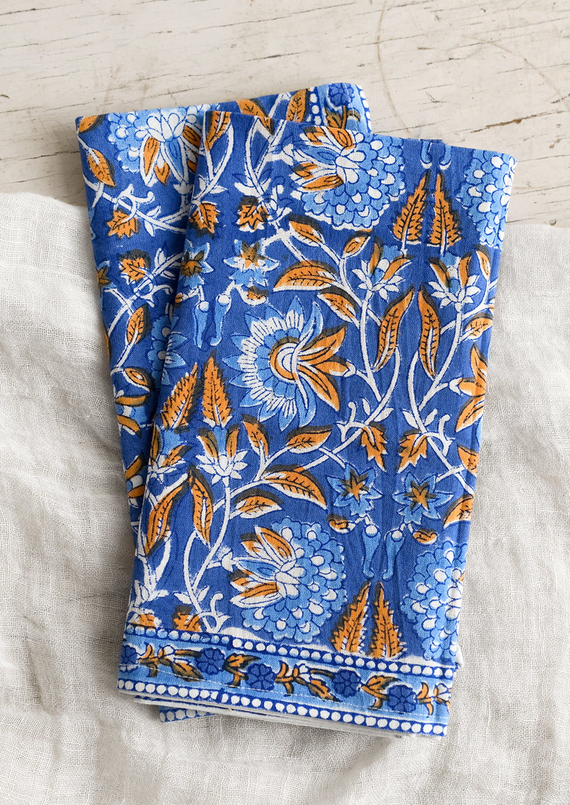 A pair of block print napkins in blue and orange floral.