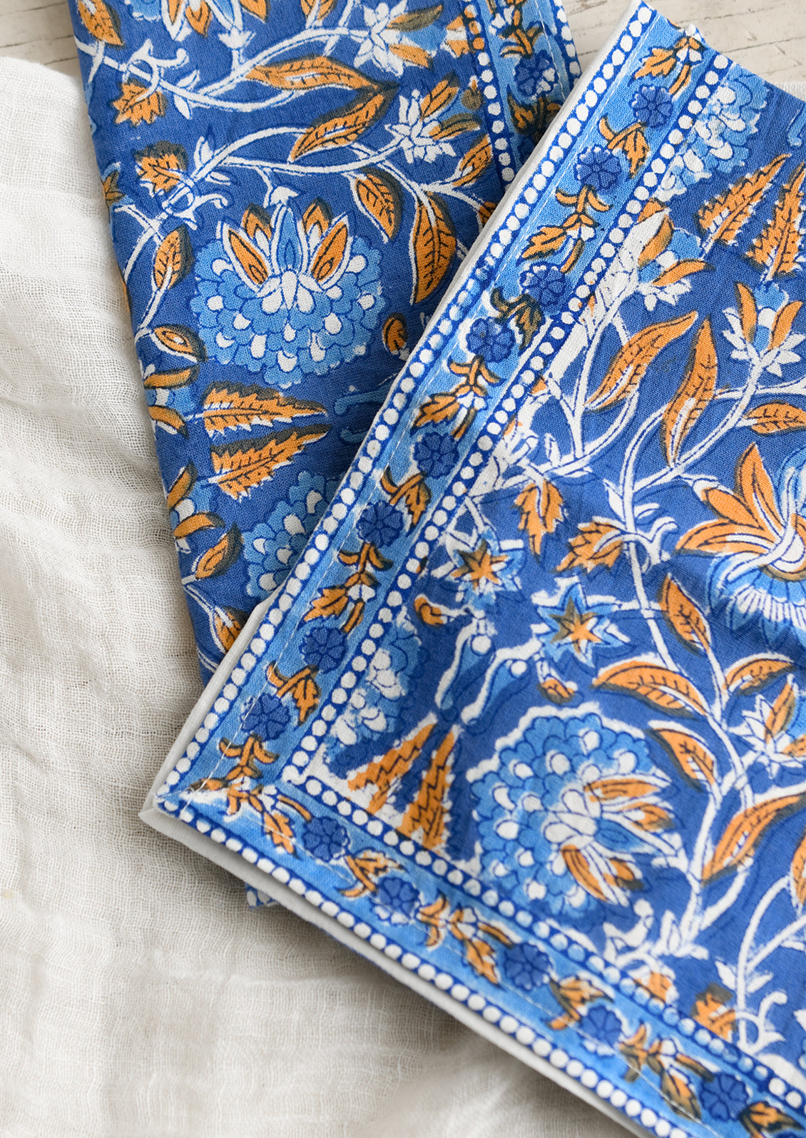A pair of block print napkins in blue and orange floral.