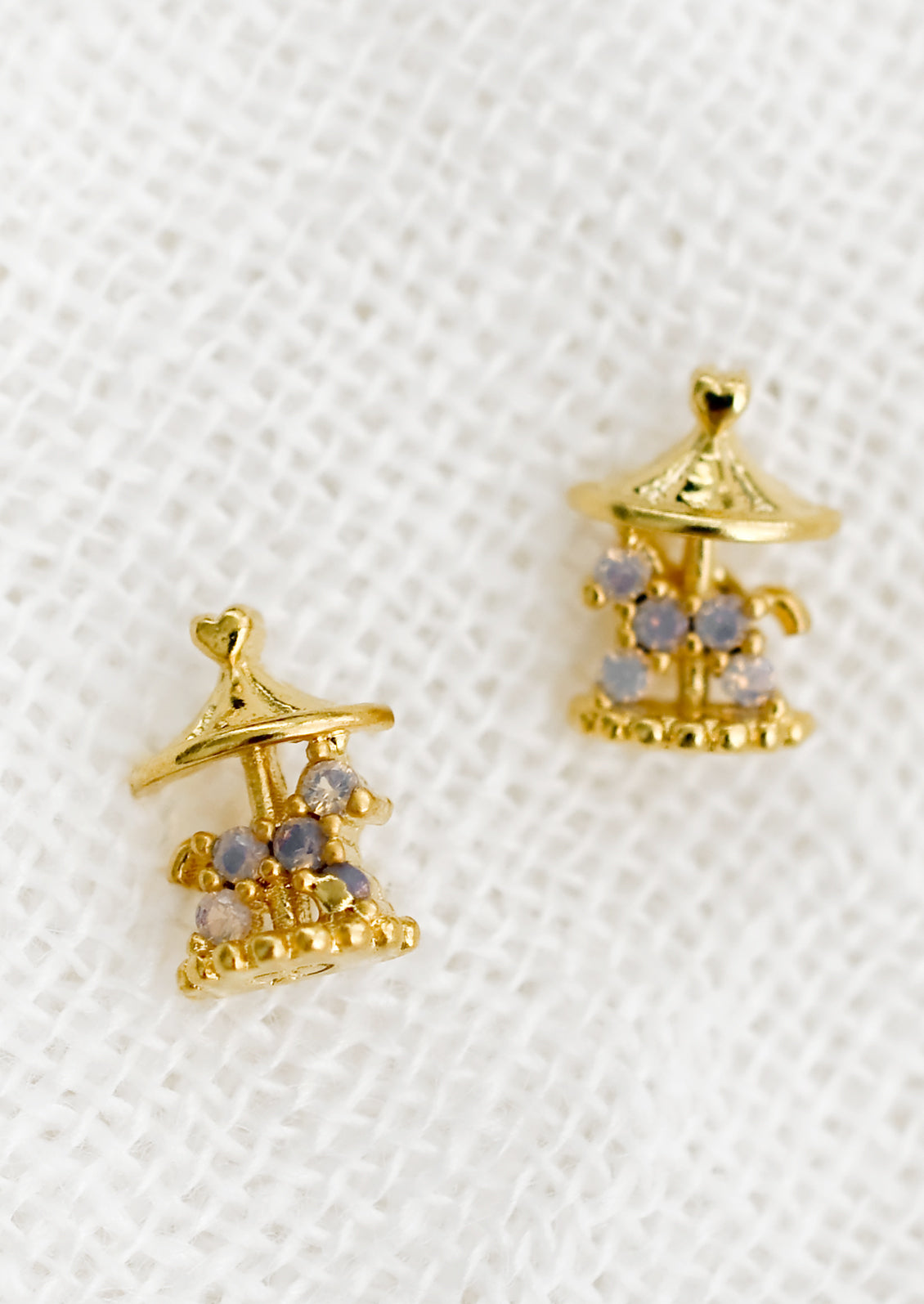 A pair of gold stud earrings in shape of carousel.