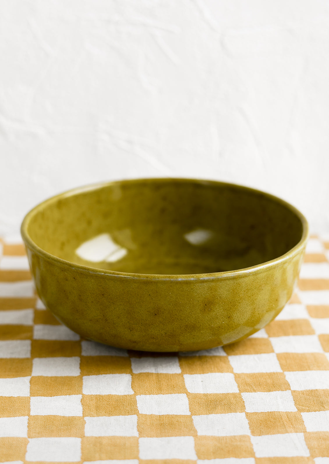 A large ceramic serving bowl in mossy green glaze.