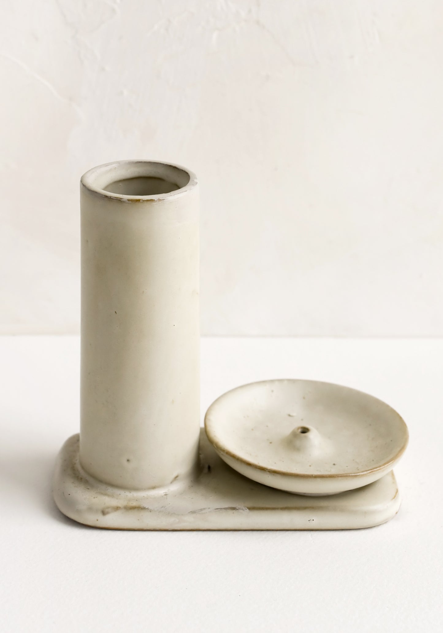 A tan ceramic incense holder with stand and incense holder.