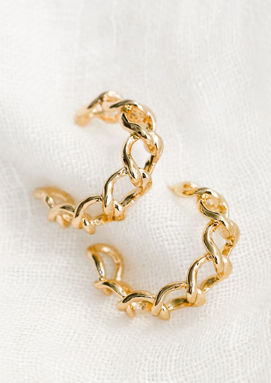 A pair of chainlink hoop earrings in gold.