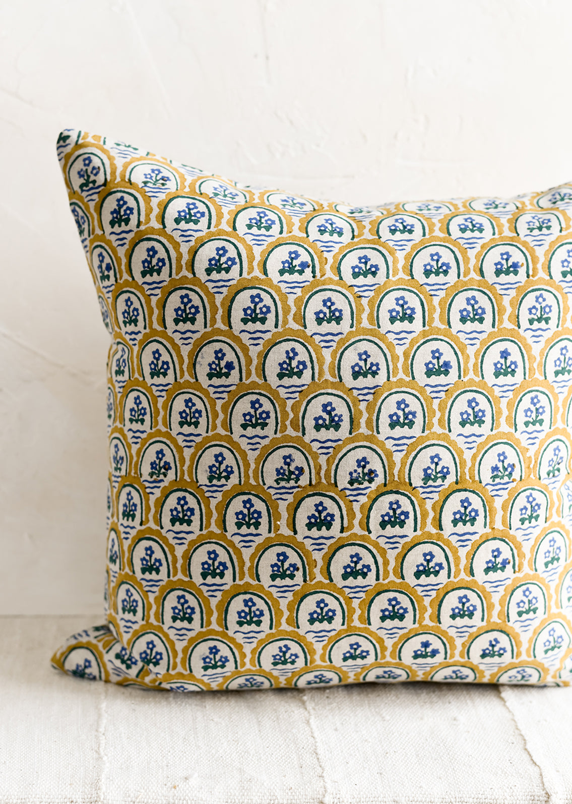 A block printed pillow with yellow and blue floral motif.