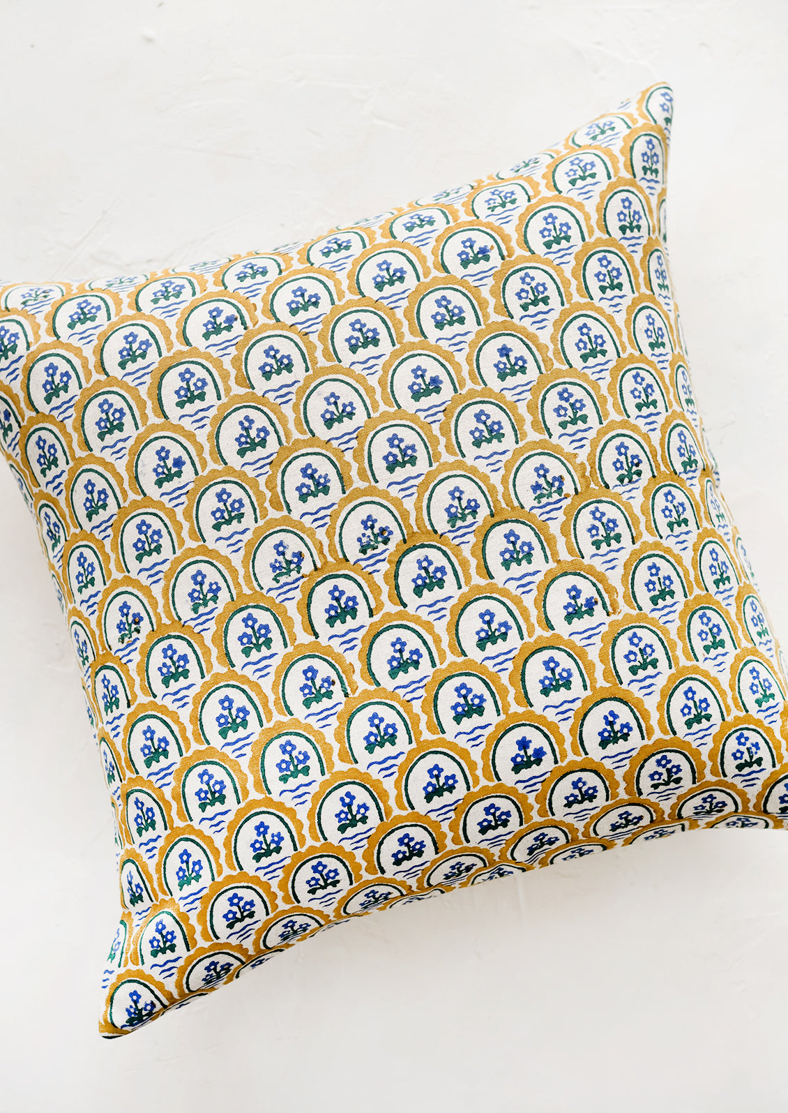 A block printed pillow with yellow and blue floral motif.