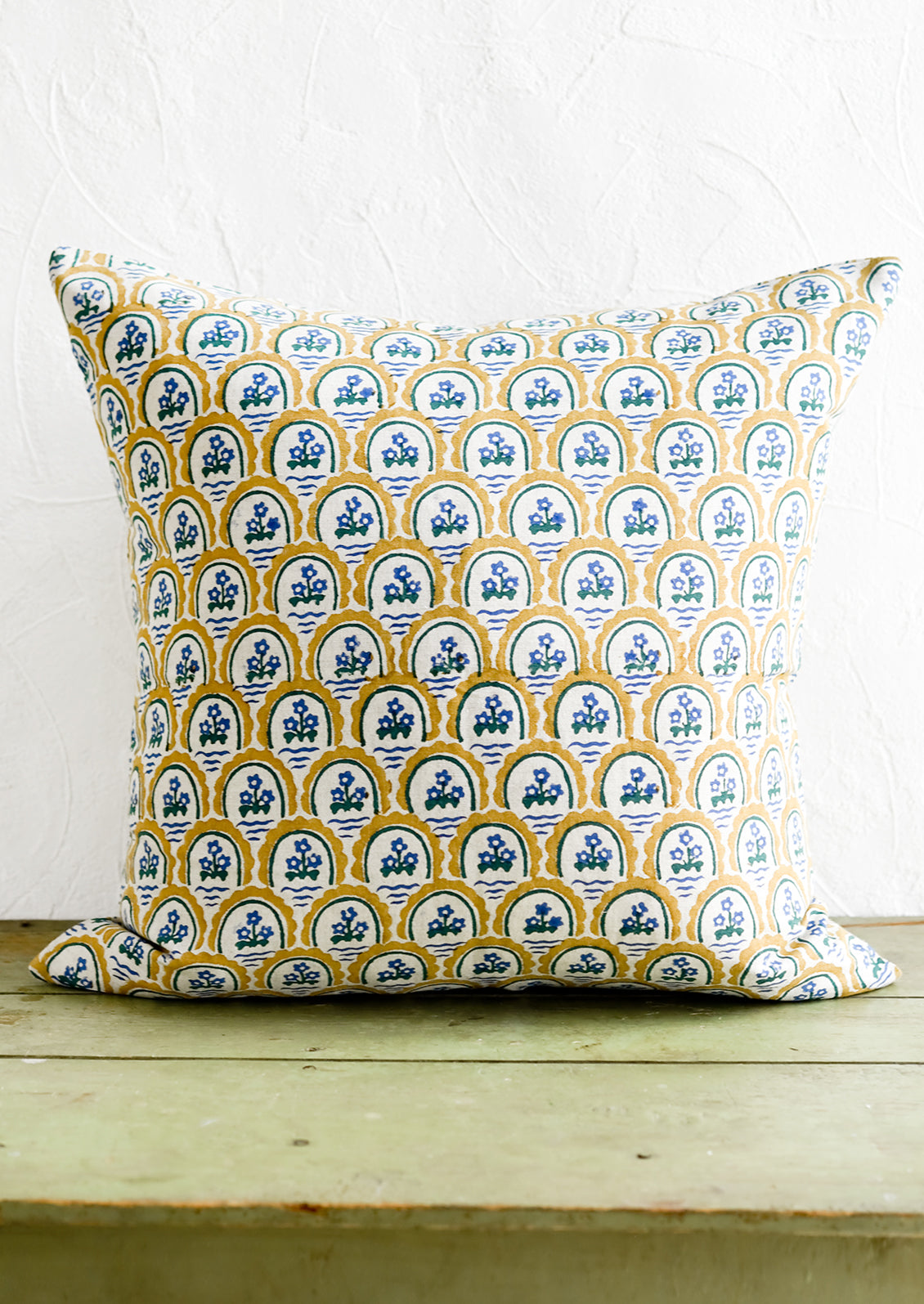 A block printed pillow with yellow and blue floral motif.