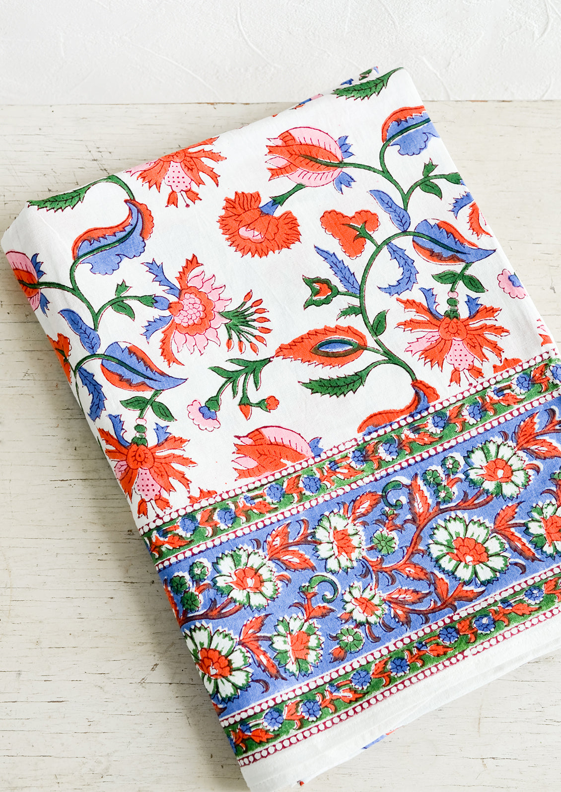A colorful block printed cotton tablecloth folded on a table.