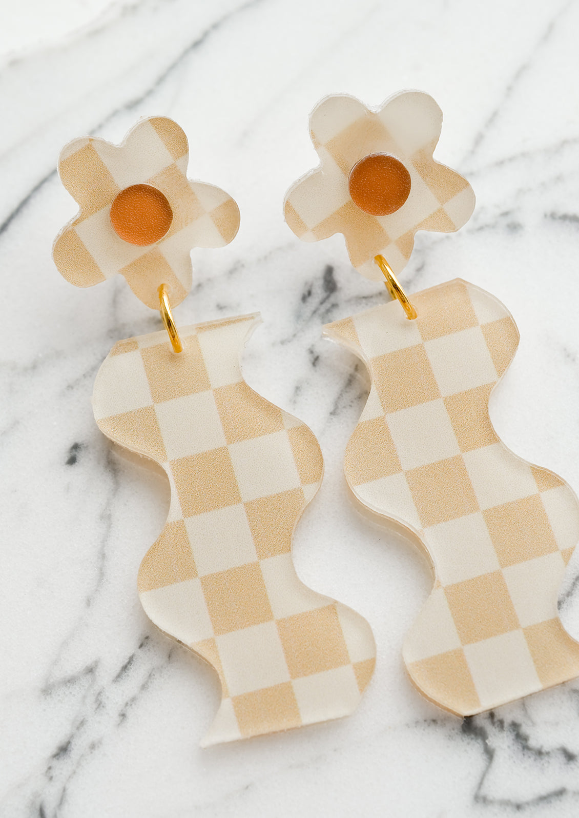 A pair of beige checker print earrings in wavy flower shape.