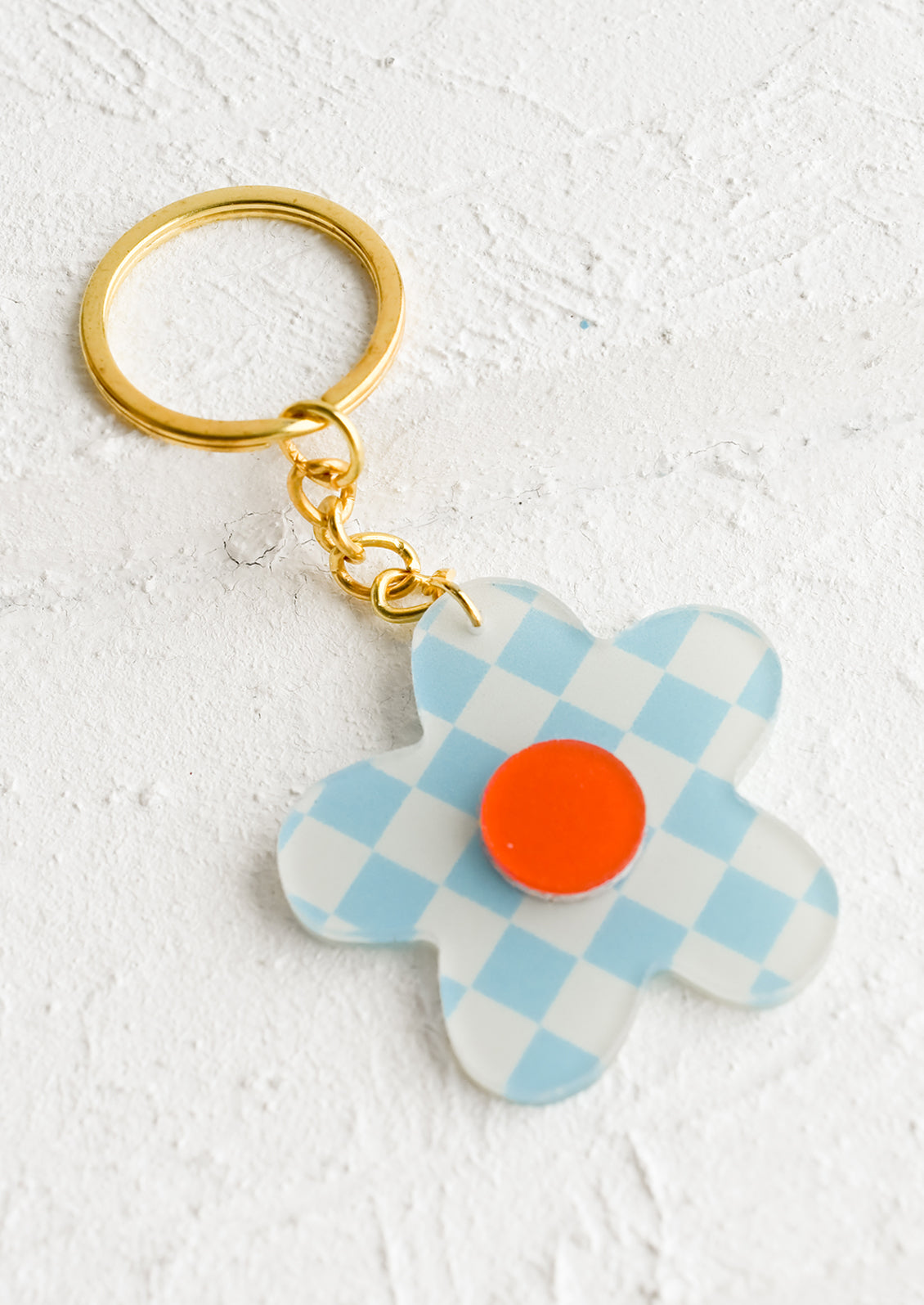 A flower shaped keychain in sky blue checker print with red center.