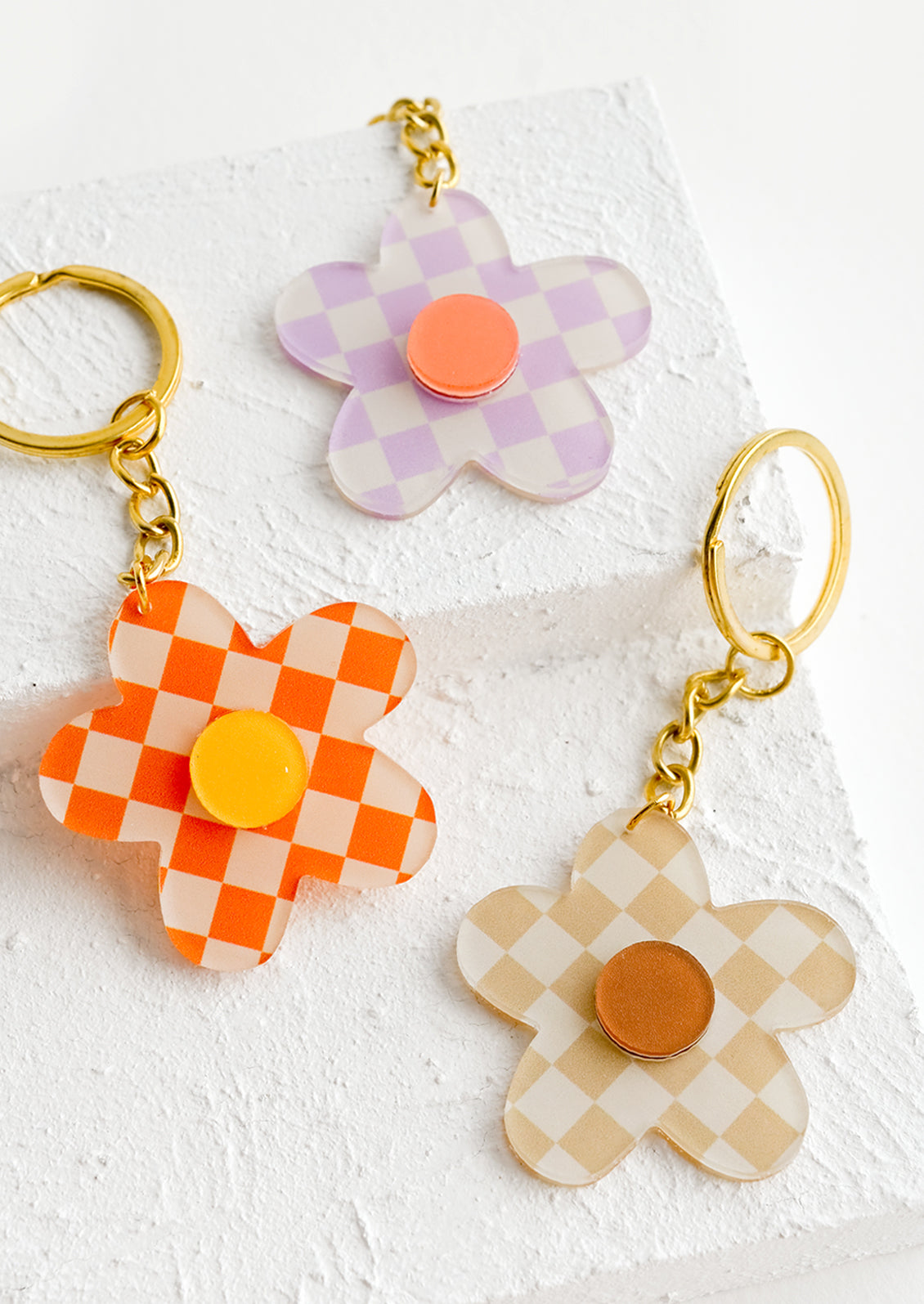 Three flower shaped keychains in checkerboard pattern in assorted colors.
