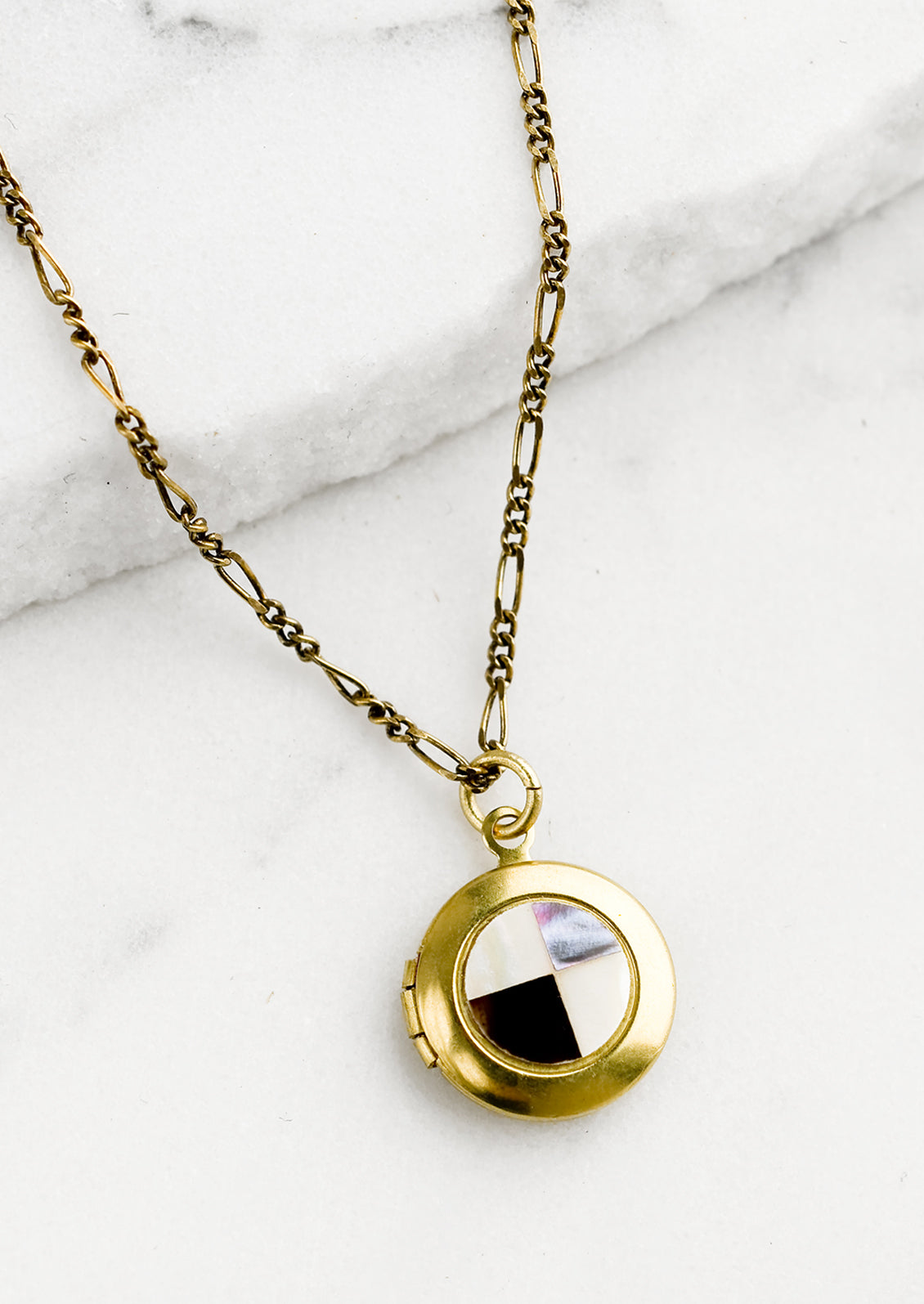 A round locket necklace with checkered abalone shell inlay.