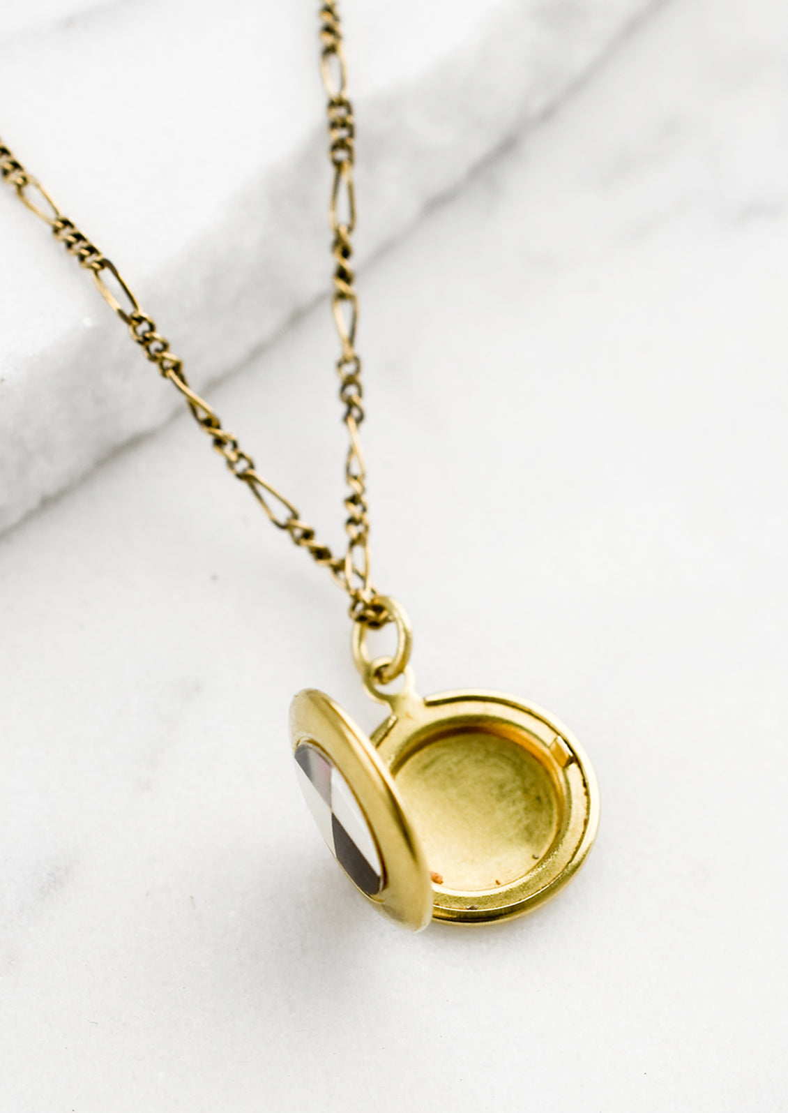 A round locket necklace with checkered abalone shell inlay, shown open.