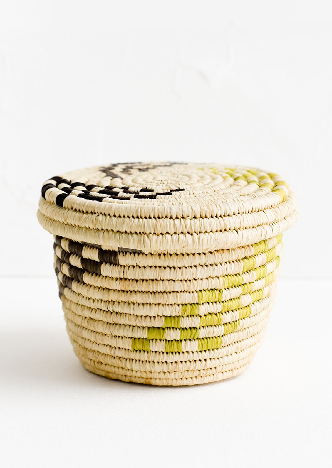 A small raffia lidded basket with woven checkered pattern.